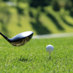 Golf club with golf ball on a tee on grass